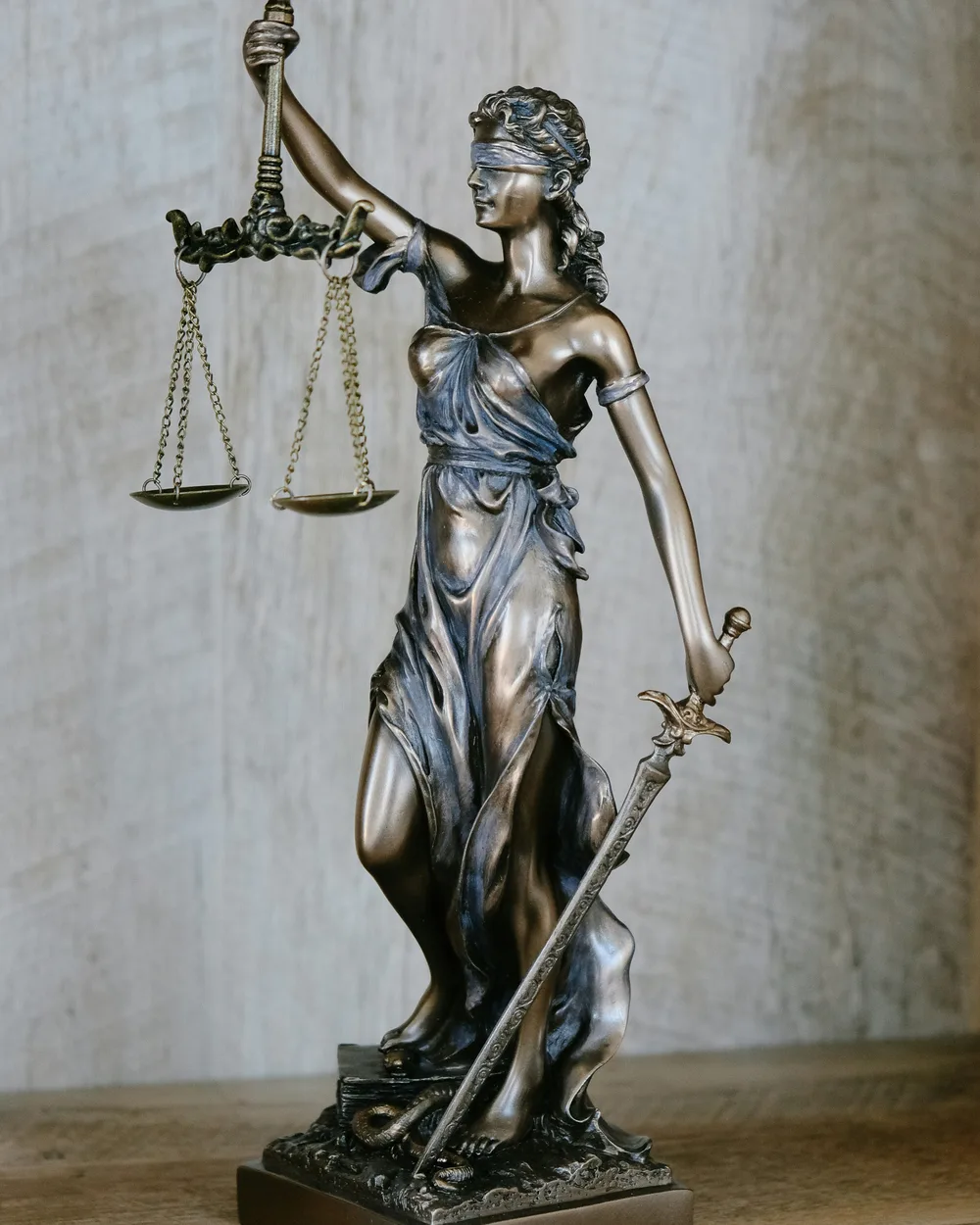 A bronze figure of Lady Justice holding balanced scales